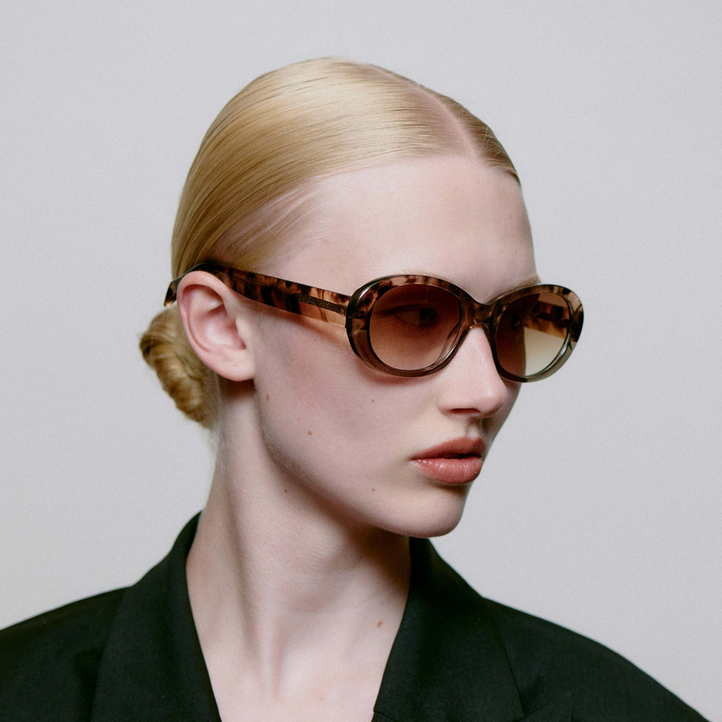Anma is medium sized style with a rounded frame with more body along the side of the frames, which gives a powerful and strong expression. They feature a mottled pattern in neutral tones, with light sepia lenses.