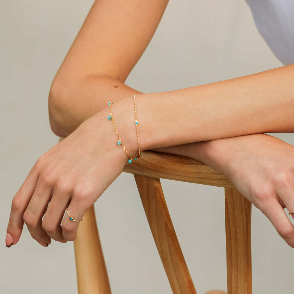 A December Birthstone charm with a vibrant turquoise sits in a bezel setting on a minimal and modern rolo chain bracelet.