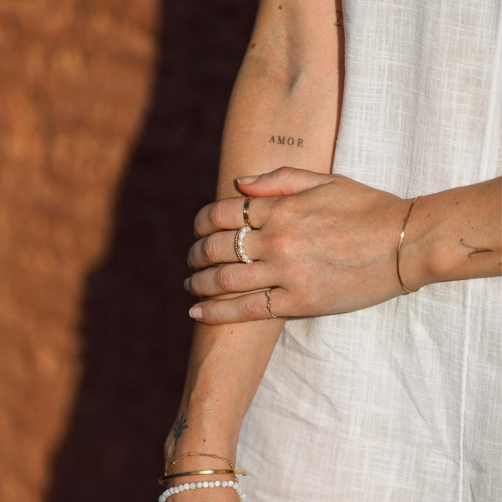 Wanderlust Life Deep Dive Pearl Ring. White freshwater pearls are strung on an elastic to form a beaded style ring. This minimal and playful take on the pearl trend and is a perfect statement ring for summer.