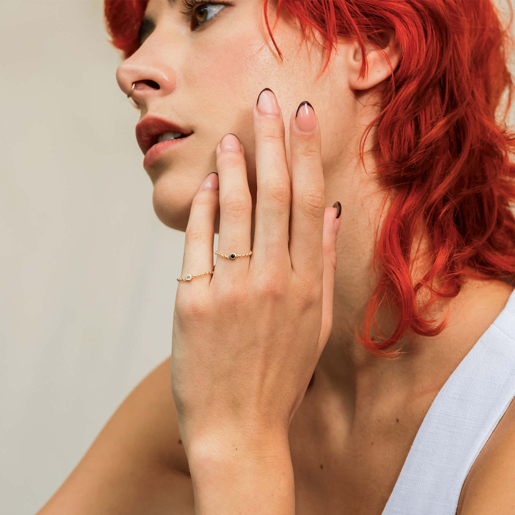 A November Chain Ring features a vibrant topaz charm on a modern Rolo chain ring. Styled with a matching Sapphire charm chain ring.